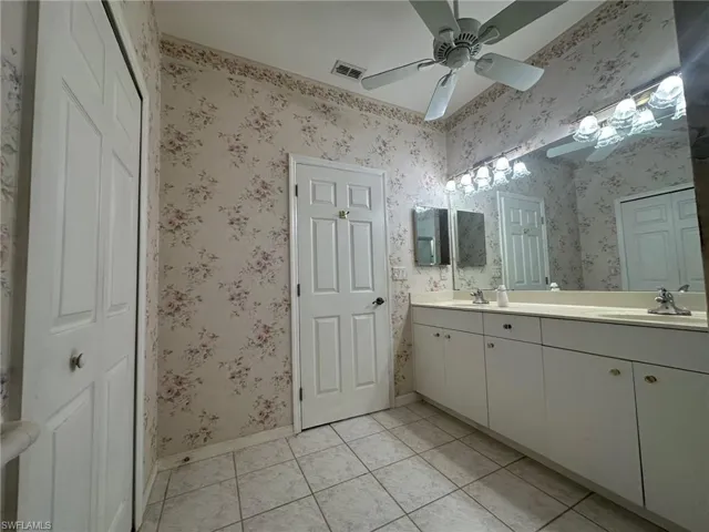 Full bath featuring baseboards, tile patterned flooring, double vanity, and a sink