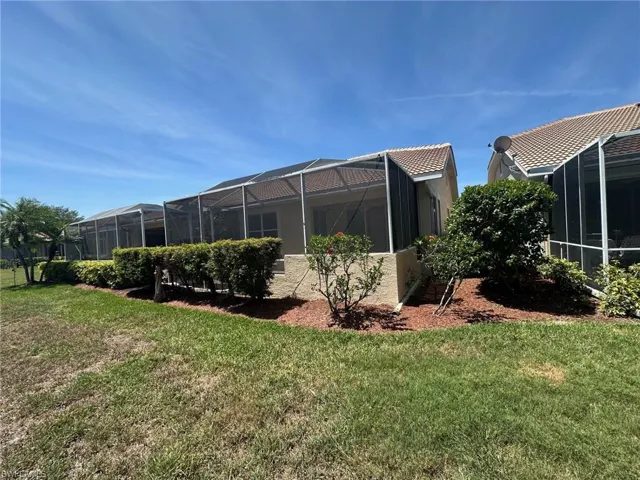 Rear view of house with glass enclosure, stucco siding, and a lawn