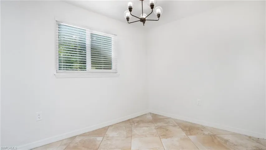 Unfurnished room featuring a chandelier and baseboards