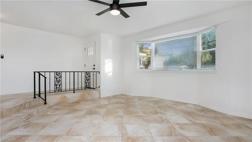 Tiled empty room with a ceiling fan and baseboards