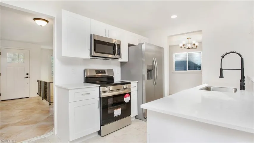 Kitchen featuring stainless steel appliances, healthy amount of natural light, a chandelier, white cabinetry, and recessed lighting