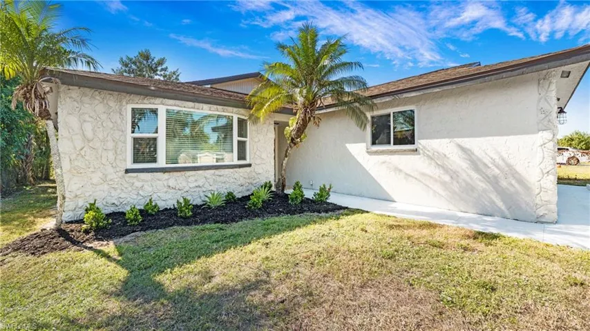 View of front of house featuring stucco siding and a front lawn