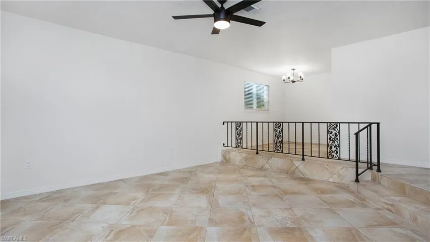 Unfurnished room with a chandelier and ceiling fan
