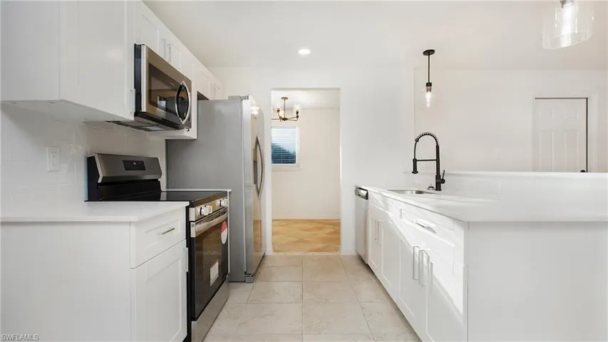 Kitchen with stainless steel appliances, backsplash, white cabinets, light countertops, and recessed lighting