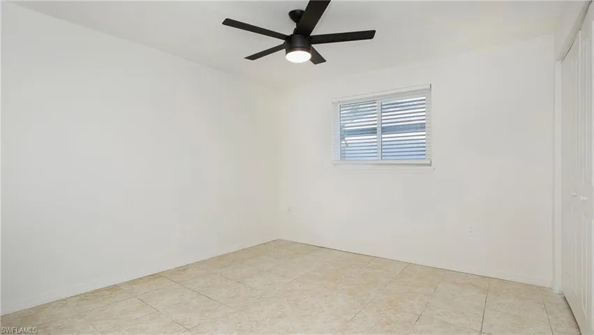 Empty room with ceiling fan and light tile patterned floors