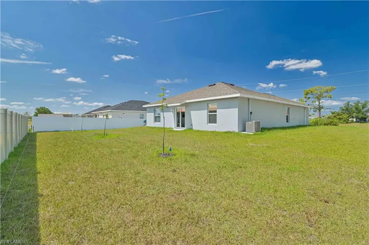 Back of property featuring cooling unit and a yard