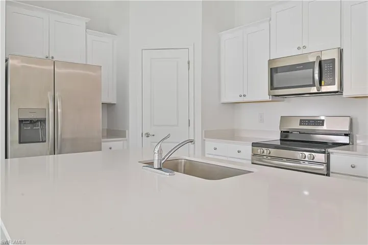 Kitchen featuring white cabinets, stainless steel appliances, and sink