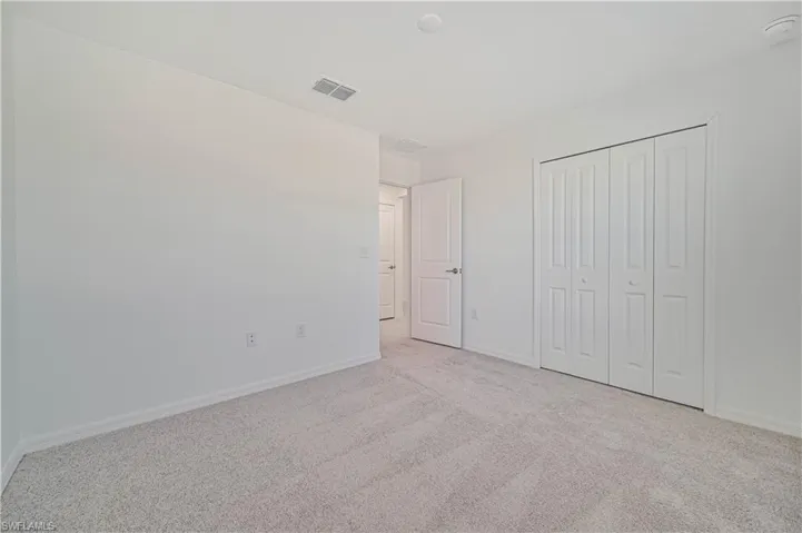 Unfurnished bedroom featuring light colored carpet and a closet