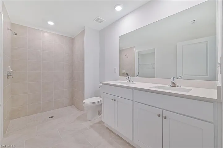 Bathroom with vanity, tile patterned floors, toilet, and tiled shower