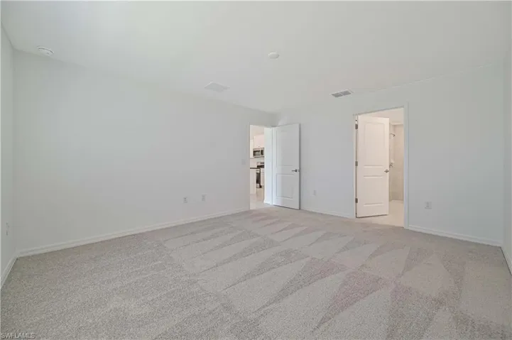 Unfurnished bedroom featuring connected bathroom and light colored carpet