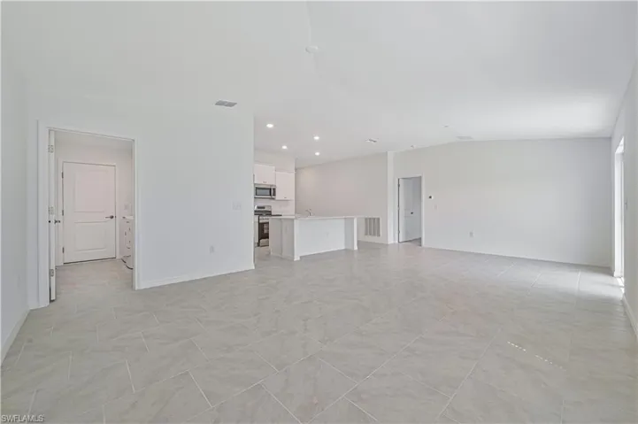 Unfurnished living room featuring vaulted ceiling