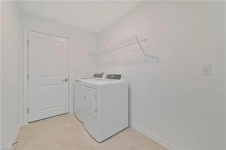 Laundry area featuring light tile patterned floors and washing machine and dryer
