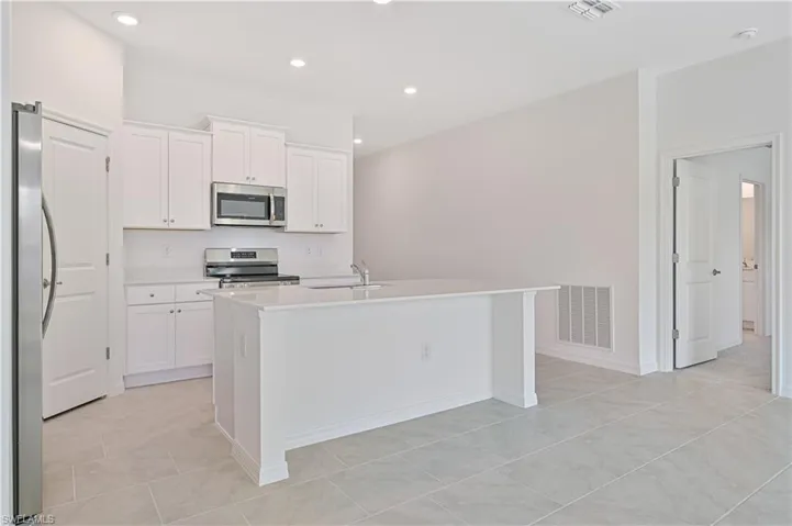 Kitchen featuring white cabinets, an island with sink, and appliances with stainless steel finishes