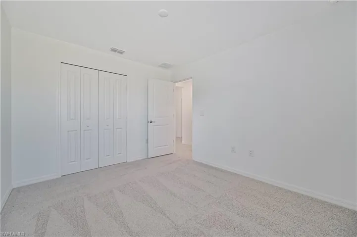 Unfurnished bedroom featuring light carpet and a closet
