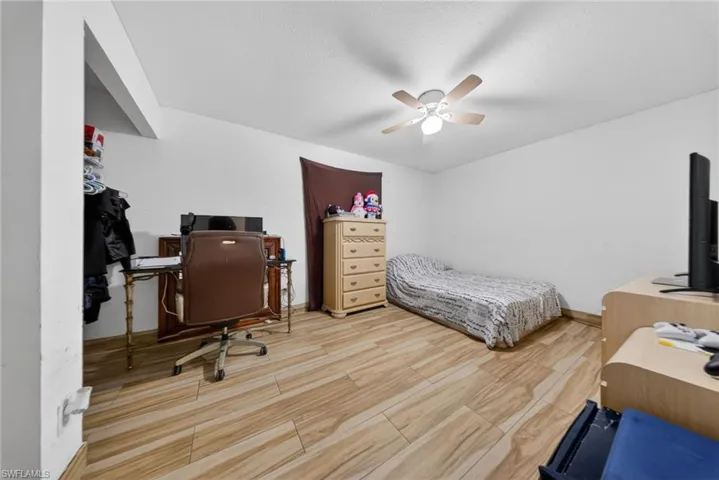 Bedroom with an office area, a ceiling fan, and light wood-type flooring