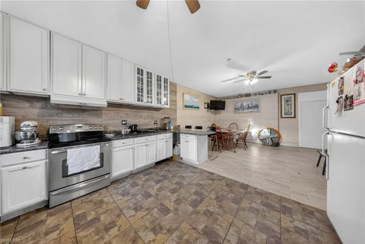 Kitchen featuring stainless steel range with electric cooktop, ceiling fan, freestanding refrigerator, glass fronted cabinets, and white cabinetry