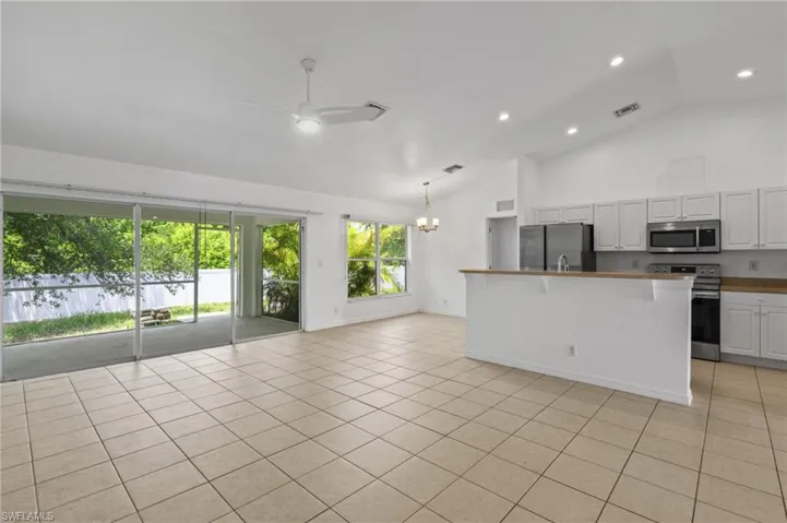 Kitchen featuring appliances with stainless steel finishes, a chandelier, ceiling fan, light tile patterned floors, and open floor plan