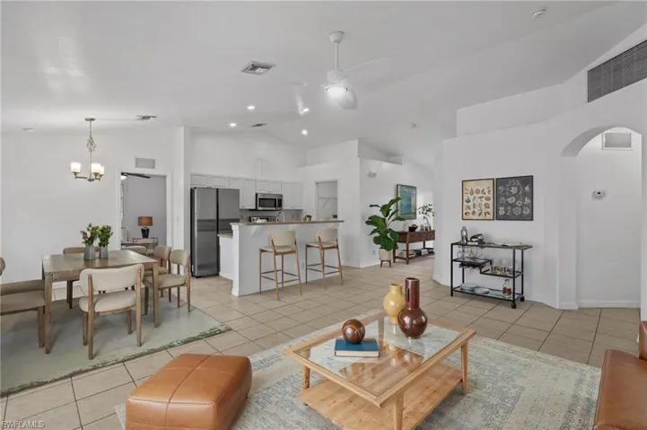 Virtually Staged! Living area featuring a ceiling fan, arched walkways, light tile patterned flooring, high vaulted ceiling, and a chandelier