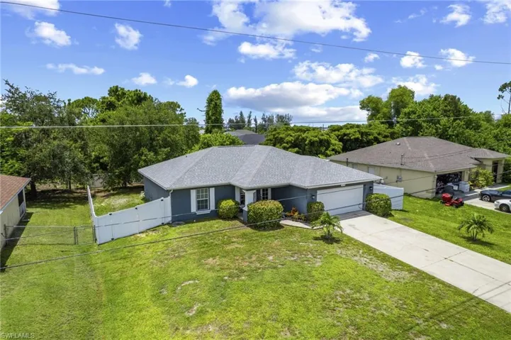 Ranch-style home with an attached garage, driveway, a shingled roof, stucco siding, and a gate