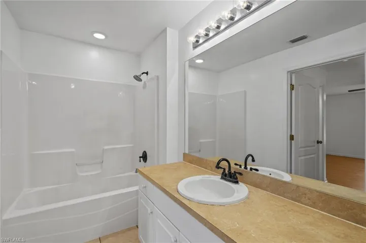 Bathroom with vanity, shower / washtub combination, and recessed lighting