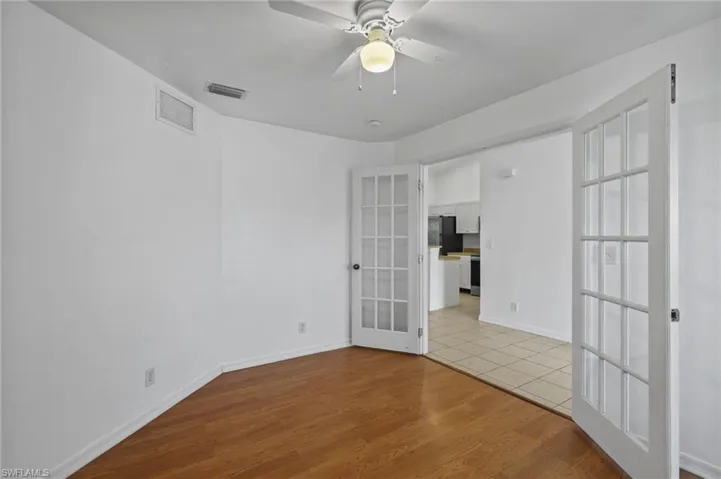 Empty room featuring french doors, ceiling fan, and light wood-style floors
