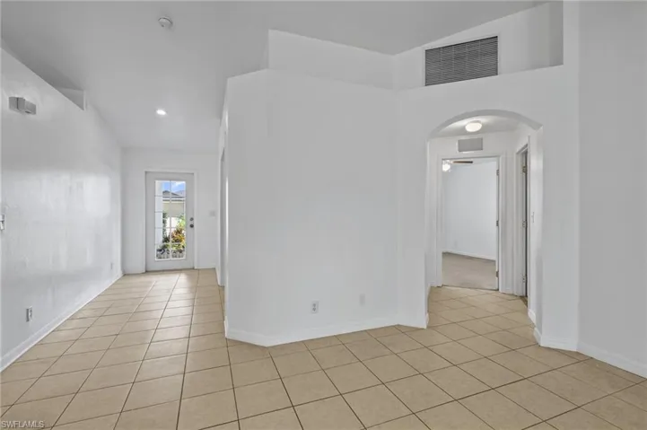 Unfurnished room featuring light tile patterned floors, arched walkways, a smoke detector, and recessed lighting