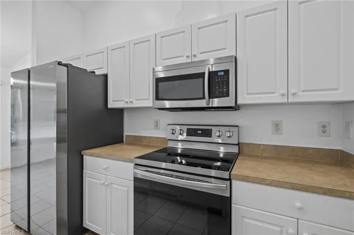 Kitchen featuring appliances with stainless steel finishes, tile patterned flooring, and white cabinets