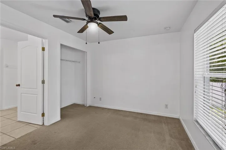 Unfurnished bedroom with light colored carpet, a closet, and ceiling fan