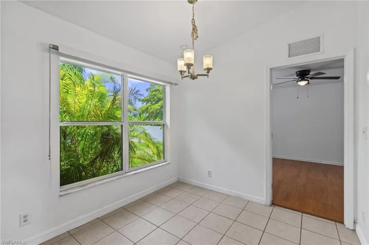 Empty room featuring plenty of natural light, a chandelier, light tile patterned floors, and a ceiling fan