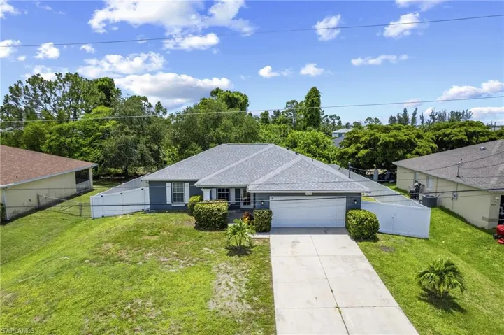 Ranch-style home with an attached garage, driveway, roof with shingles, and a gate