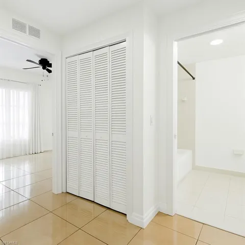 Corridor with light tile patterned flooring and baseboards