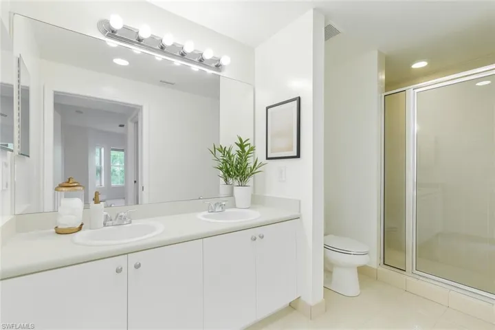 Full bath featuring double vanity, a stall shower, and tile patterned floors
