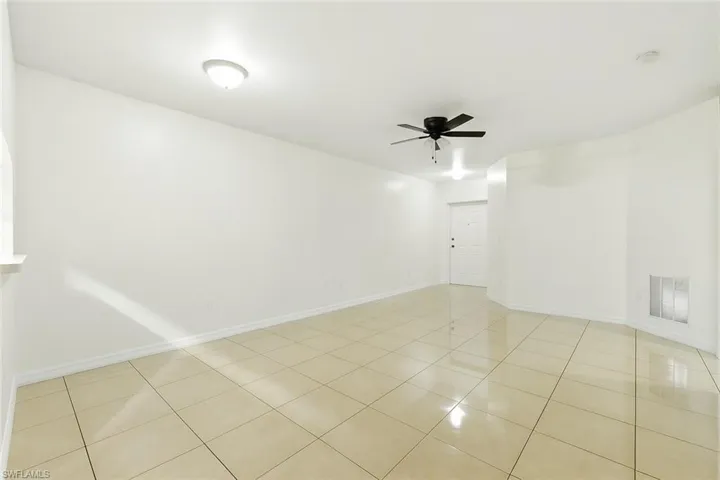 Spare room with ceiling fan, light tile patterned floors, and a smoke detector