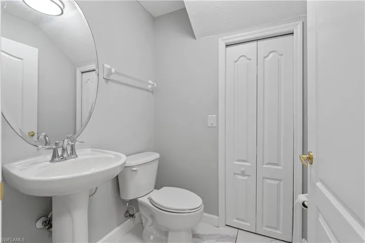 Half bath featuring a closet and light marble finish flooring