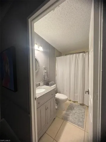 Full bathroom featuring vanity, a textured ceiling, tile patterned flooring, and a shower with shower curtain