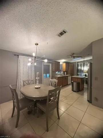 Dining area featuring a chandelier, a textured ceiling, and light tile patterned floors