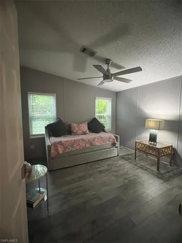 Guest Bedroom featuring wood finished floors, a ceiling fan, lofted ceiling, and a textured ceiling