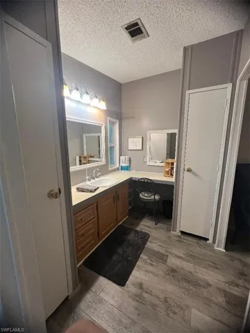 Bathroom with wood finished floors, a textured ceiling, and vanity