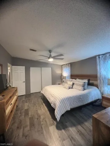 Bedroom with wood finished floors, a closet, a textured ceiling, and a ceiling fan