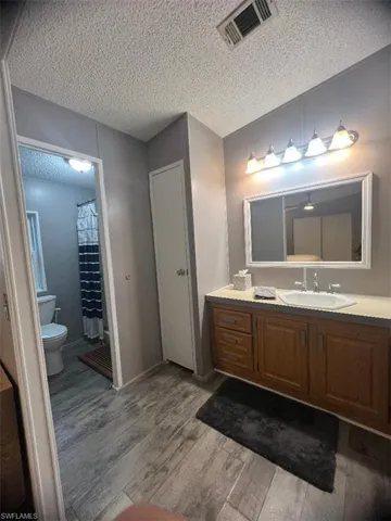 Full bath featuring wood finished floors, a textured ceiling, and vanity