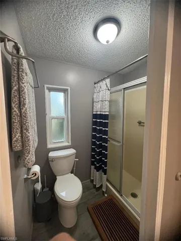 Bathroom with a shower stall and a textured ceiling