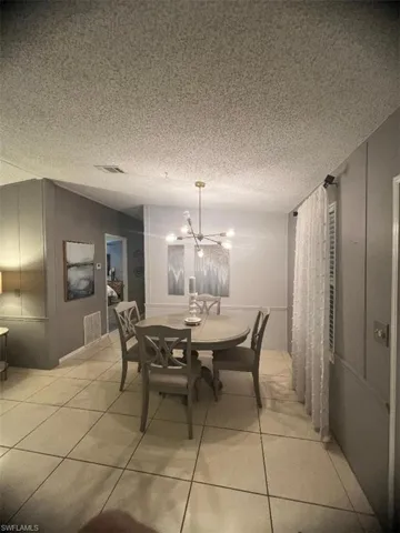 Dining space with a chandelier, light tile patterned flooring, and a textured ceiling