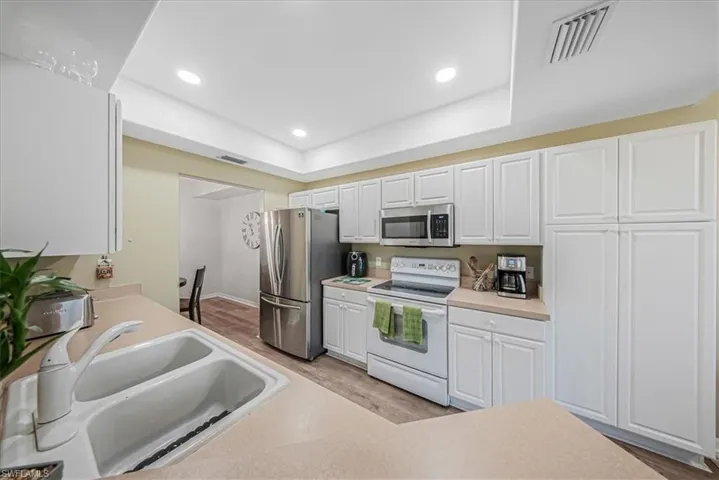 Kitchen featuring stainless steel appliances, light countertops, light wood-type flooring, white cabinetry, and recessed lighting