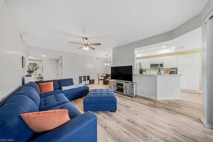 Living area with light wood finished floors, a chandelier, recessed lighting, ceiling fan, and a raised ceiling