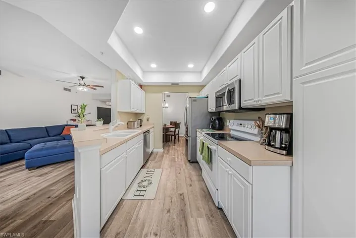 Kitchen featuring open floor plan, white cabinets, appliances with stainless steel finishes, light countertops, and recessed lighting