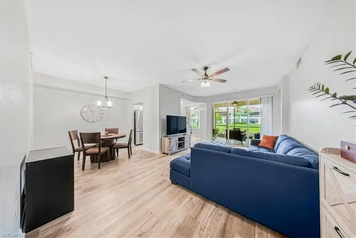 Living area with light wood-style floors, ceiling fan, and a chandelier