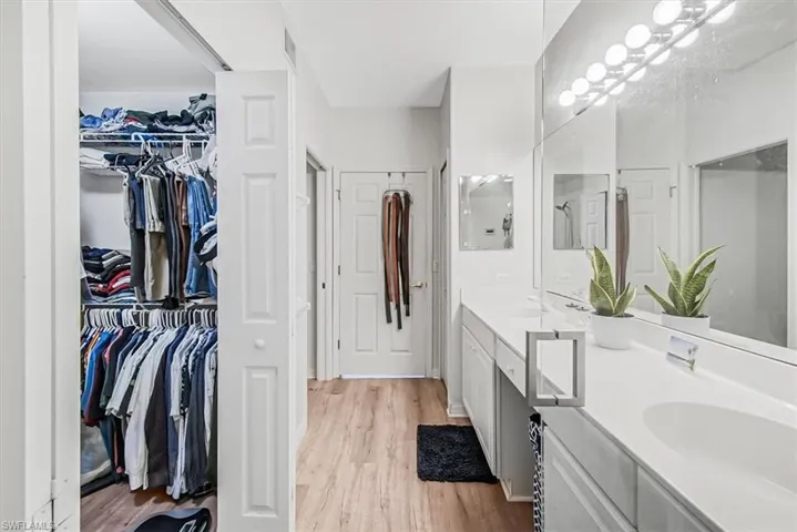 Full bathroom featuring double vanity, light wood-style floors, and a spacious closet