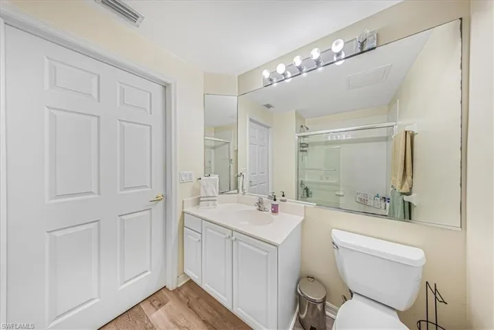 Full bath with vanity, light wood-style floors, and a shower stall