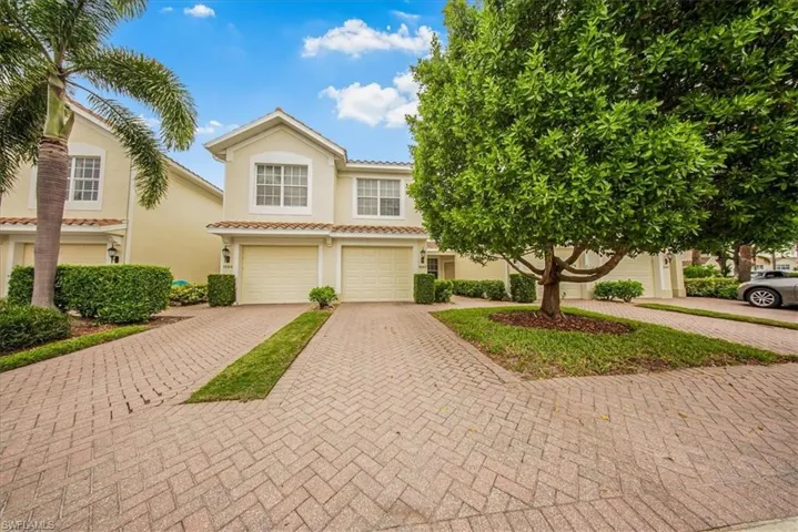 View of front of house with decorative driveway, an attached garage, stucco siding, and a tiled roof