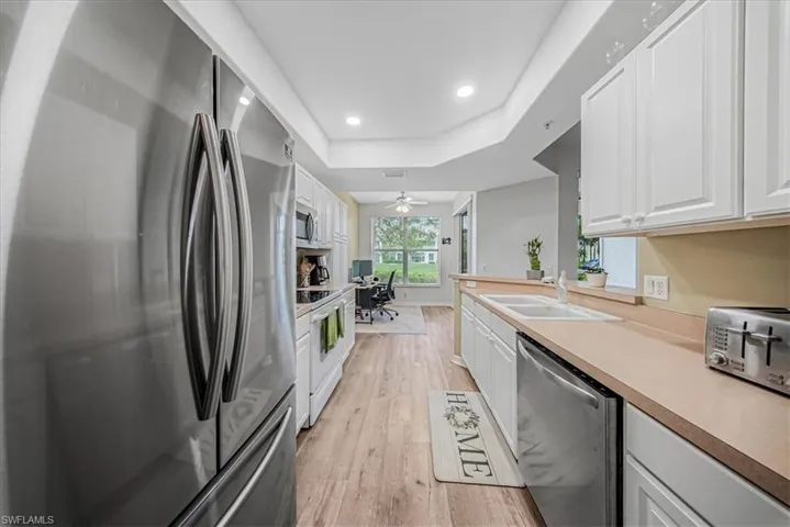 Kitchen with stainless steel appliances, white cabinets, light countertops, and recessed lighting